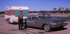 a man standing next to an old car in front of a camper and trailer