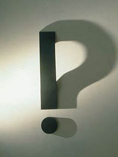 the shadow of a question mark on a white wall with a black object in front of it