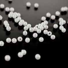 white pearls are scattered on a black surface