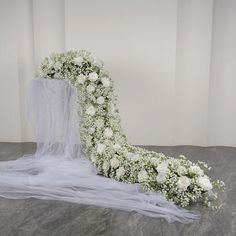 a wedding arch with white flowers and veil on the floor in front of a wall