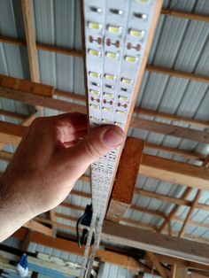 a hand is holding up a light fixture in a room with exposed ceilings and beams