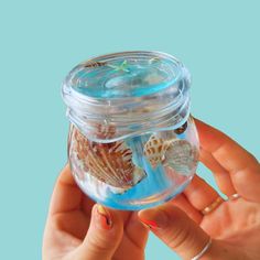 a person holding a jar filled with sea shells