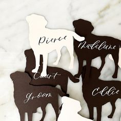 four dog cutouts with names on them sitting on a marble counter top next to each other