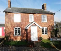 a red brick house with white doors and windows on the front, next to a gravel driveway