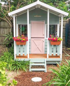 a small shed with flowers in the window boxes on the front door and steps leading up to it