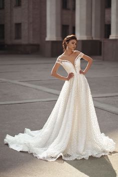 a woman in a white wedding dress posing for the camera with her hands on her hips