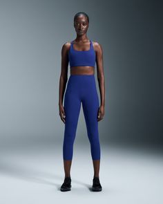 a woman in blue sports bra top and leggings posing for a studio shot