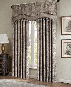 a living room with curtains and pictures hanging on the wall next to a rug in front of a window