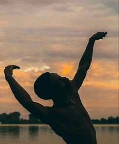 a shirtless man reaching up to catch a frisbee in front of the water