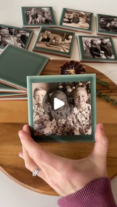 a person holding up an old photo in front of many other photos on a table