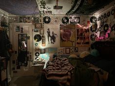 a room filled with lots of clutter and pictures on the wall next to a bed