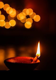 a lit candle sitting on top of a wooden table next to a blurry background