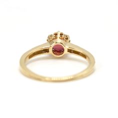 a yellow gold ring with an oval ruby stone in the center and two small diamonds on each side