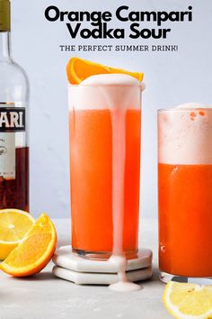 two glasses filled with orange juice next to an empty bottle and some sliced oranges