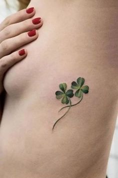 a woman's stomach with a four leaf clover tattoo on her left side ribcage