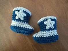 two crocheted blue and white baby booties sitting on top of a wooden table