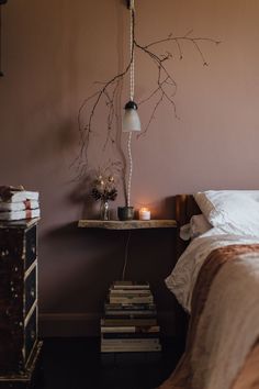 a bedroom with a bed, lamp and books on the nightstand next to the bed