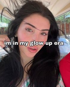 a woman with long black hair holding her head in front of her face and the words i'm in my glow up era