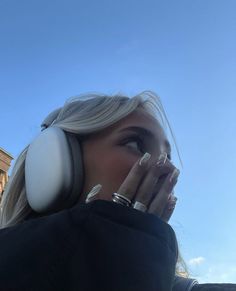 a woman with headphones on her ears is looking up at the sky in front of a building