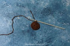 a crochet hook is laying on the ground next to a yarn ball and knitting needles