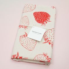 a folded piece of cloth with strawberries printed on it and a white tag attached to the fabric