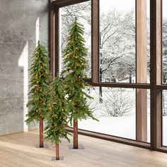 a small christmas tree sitting in front of a window next to a snow covered forest