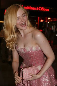 a woman in a pink dress is smiling and posing for the camera with her purse