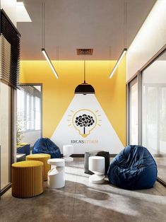 an office with yellow walls and blue bean bags on the floor, white tables and chairs