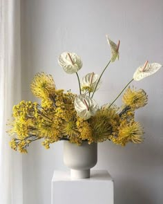 a white vase filled with yellow flowers on top of a table