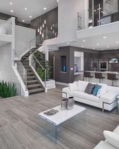 a living room filled with white furniture next to a stair case in a large open floor plan