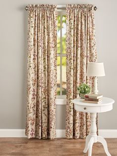 a white table sitting next to a window with curtains on top of it and a lamp in front of it