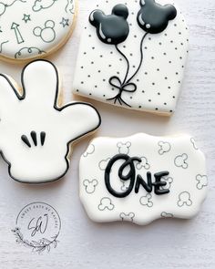 three decorated cookies with mickey mouse designs on them and the words one written in black