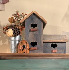 some bird houses are on a shelf with flowers in a vase and other decorations behind them