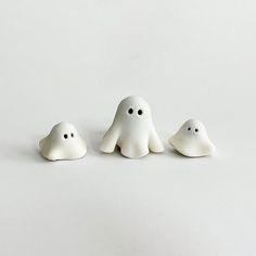 three small white ghost figurines sitting on top of a table next to each other