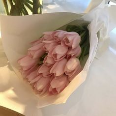 a bouquet of pink tulips sitting on top of a white tablecloth covered table