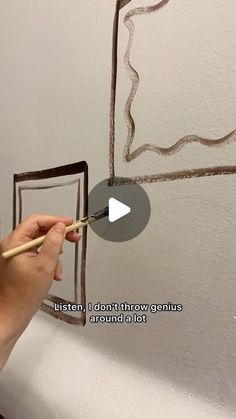 someone is painting the wall with brown paint and using a brush to draw lines on it