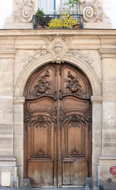 an old wooden door with two lions on it's sides and flowers in the window