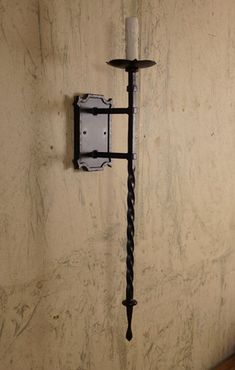 a hook on the wall with a candle in it and a light fixture attached to it