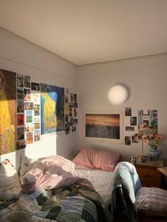 an unmade bed in a small room with pictures on the wall