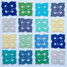 crocheted bows are arranged in rows on a white tablecloth with blue, yellow and green colors