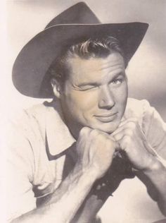 a black and white photo of a man in a cowboy hat with his hand on his chin