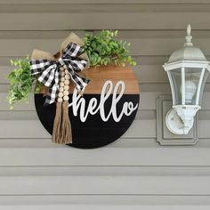 a wooden sign that says hello hanging on the side of a wall next to a lamp