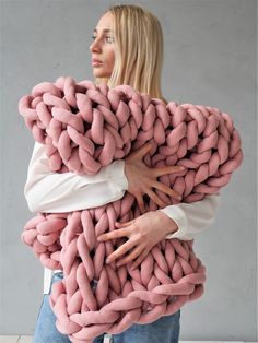 a woman is holding a giant chunky blanket