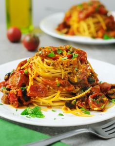 spaghetti with tomato sauce and olives on a white plate