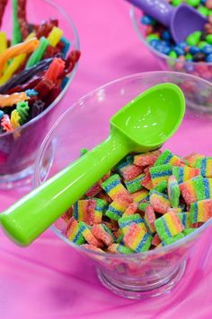 two bowls filled with candy and a green spoon on top of the bowl is full of colorful candies