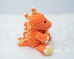 an orange crocheted stuffed animal sitting on top of a white blanket