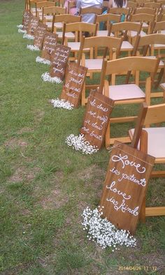 rows of wooden chairs with white flowers on them and signs attached to the back of each chair