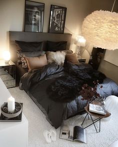 a bed with black sheets and pillows in a bedroom next to two pictures on the wall