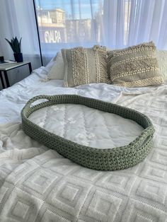 a crocheted bed frame sitting on top of a white bedspread in front of a window