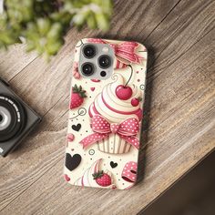 an iphone case with cupcakes and hearts on it, next to a camera